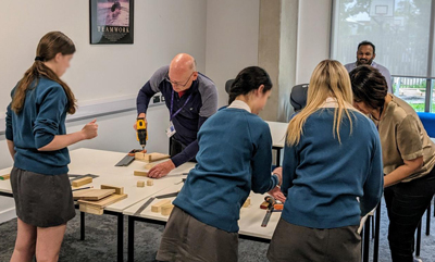 female students from Teddington School try carpentry with the help from RuTC teachers
