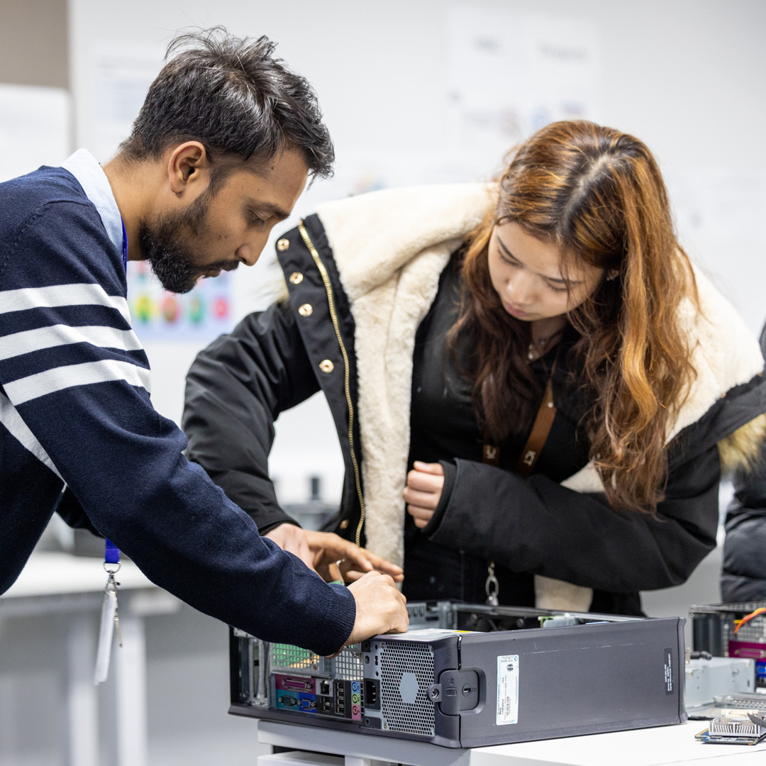 male teacher and female student working on a the the inside of a computer