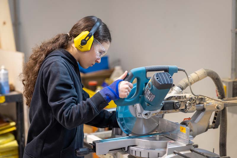 construction female student using circular saw