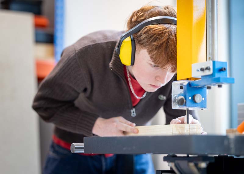 construction male student using band saw