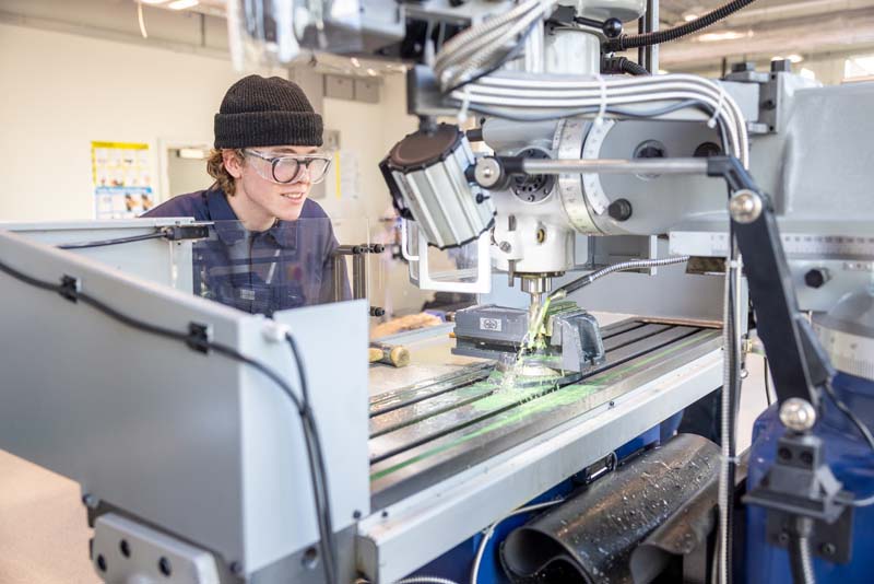 Engineering male student using industrial drill