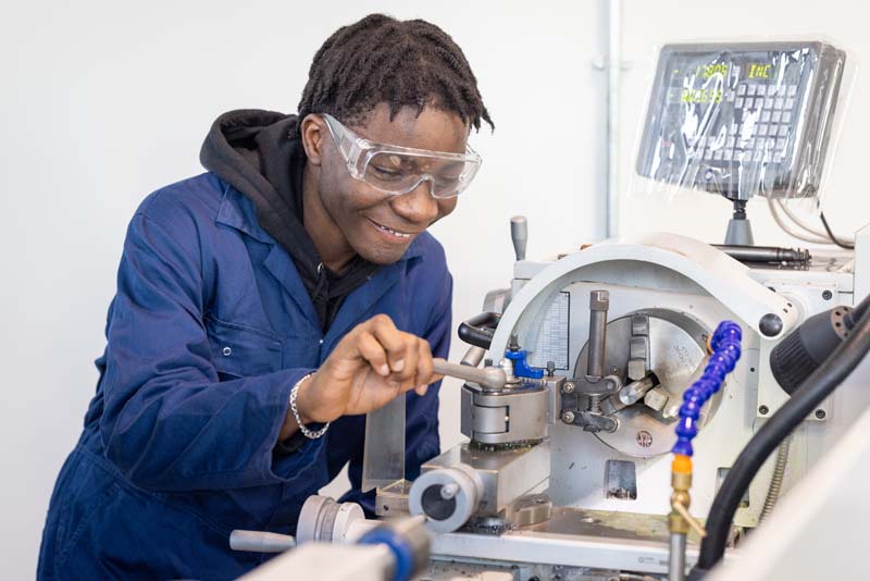 Engineering male student using machinery