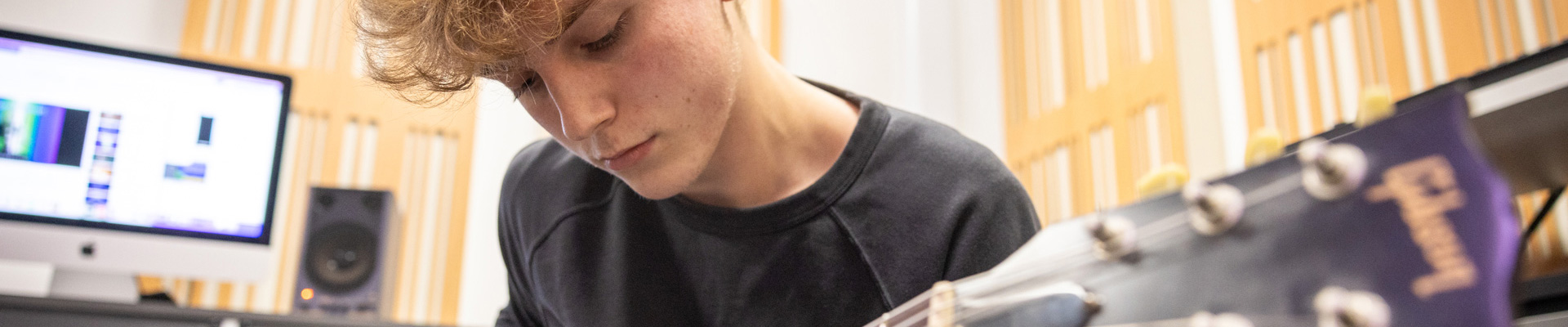 male student playing guitar