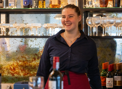 Hospitality student behind the bar smiling