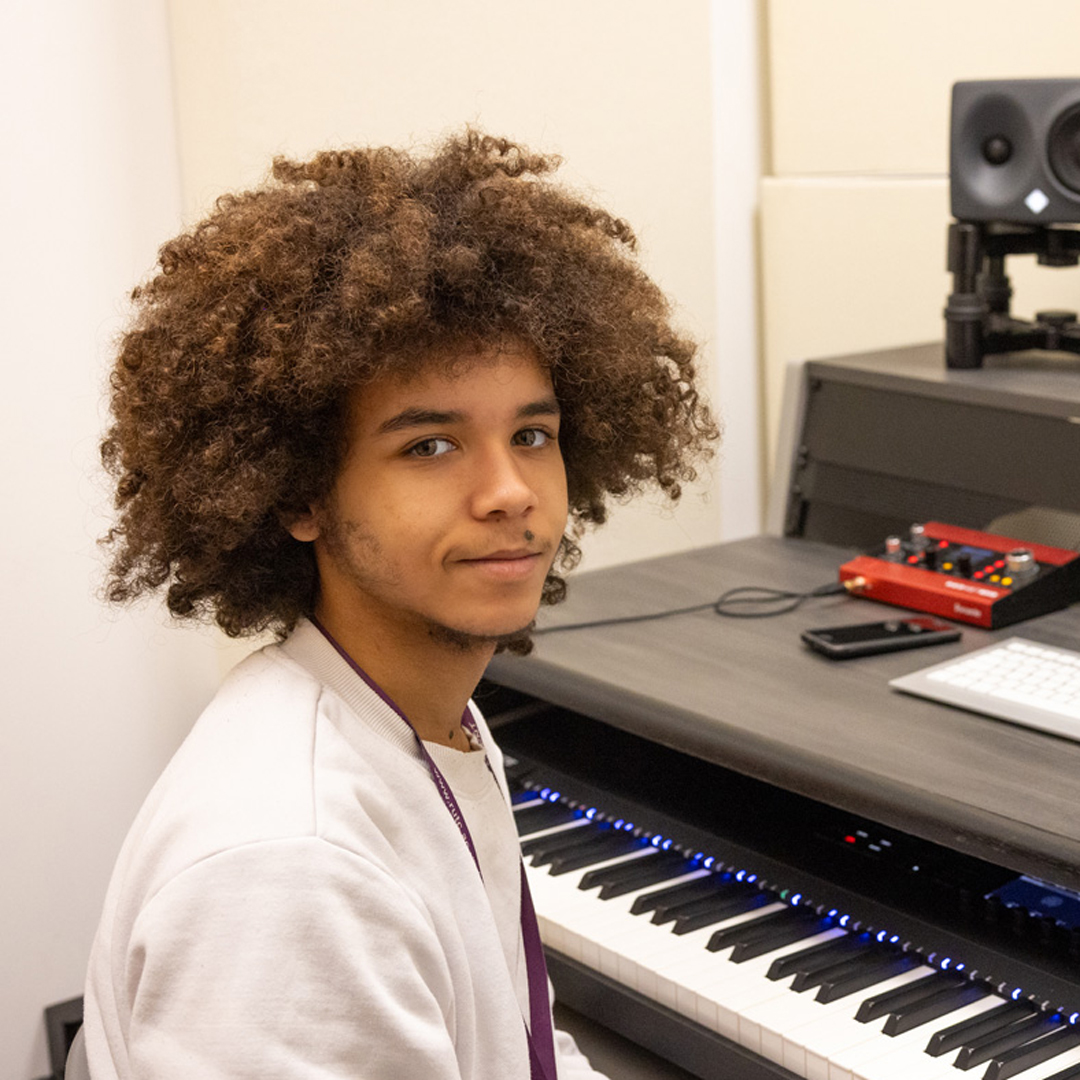 male student in music studio smiling at camera